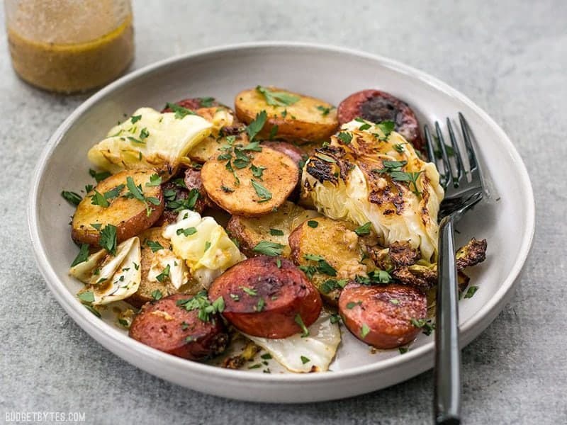 This One Pan Roasted Kielbasa and Cabbage Dinner comes together in minutes and is full of flavor and comfort. An easy weeknight dinner! BudgetBytes.com A plate full of One Pan Roasted Kielbasa and Cabbage Dinner ready to be eaten
