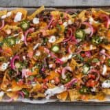 For the perfect Spicy Baked Black Bean Nachos, layer your chips and toppings for the perfect chip-to-topping ratio. BudgetBytes.com