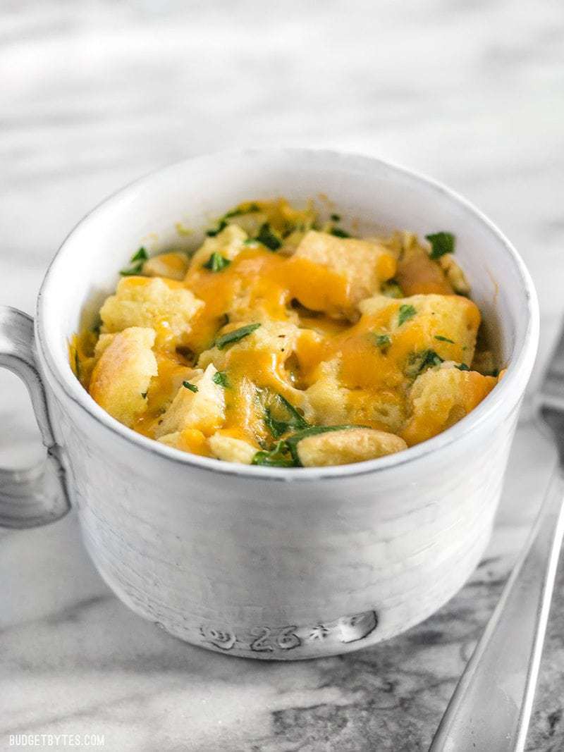 Use the leftovers in your fridge to make this delicious and filling 5 Minute Savory Microwave Breakfast Mug. Fast and easy! BudgetBytes.com A savory breakfast mug from the front, melted cheese and parsley on top