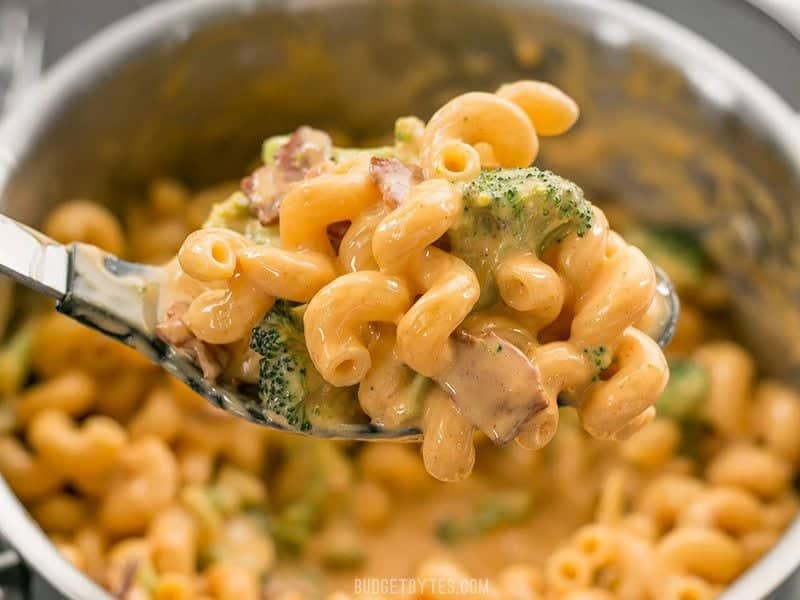 This One Pot Bacon Broccoli Mac and Cheese is fast, easy, and absolutely fool proof. This sauce stays smooth and creamy! BudgetBytes.com Close up of a spoonful of Bacon Broccoli Mac and Cheese