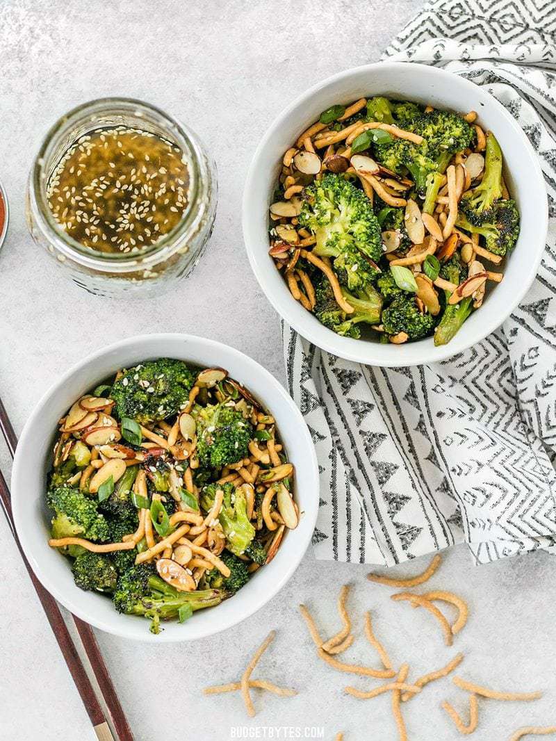 This crunchy, sweet, and salty Roasted Broccoli Salad with Almonds is my favorite way to get my vegetables and goes great with any Asian inspired meal. Budgetbytes.com Two bowls of Roasted Broccoli Salad with Almonds with a jar of Simple Sesame Dressing on the side