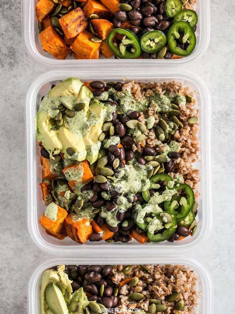 These Sweet Potato Grain Bowls with Green Tahini Sauce are prefect for meal prep and bursting with color, texture, and flavor! BudgetBytes.com Four meal prep containers of Sweet Potato Grain Bowls with Green Tahini Sauce