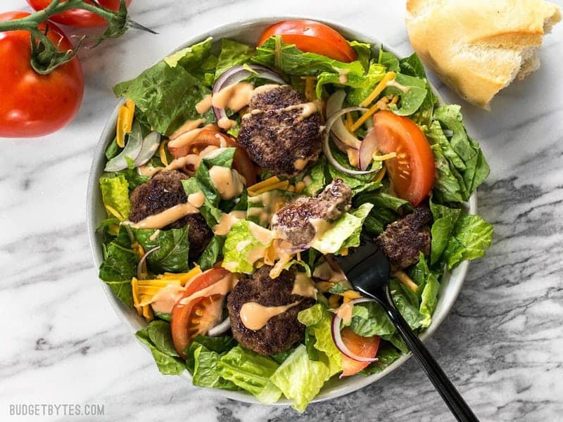 When you're got to have your burger, but you're trying to do better, make a Cheeseburger Salad! BudgetBytes.com Cheeseburger salad from above with a fork taking a bite and bread on the side
