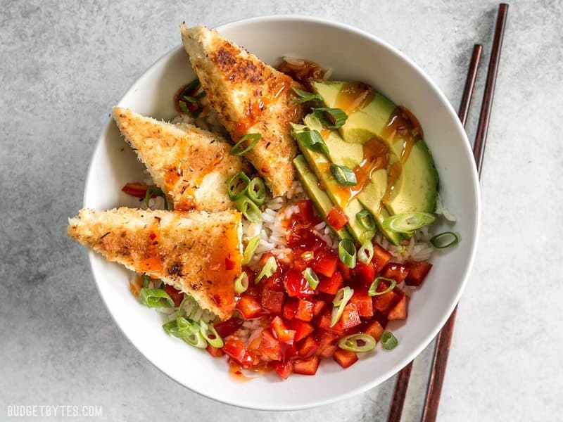 These subtly sweet Coconut Crusted Tofu dippers are the perfect vehicle for tangy sweet chili sauce. Serve as a snack or part of your favorite bowl meal. BudgetBytes.com Coconut Crusted Tofu made into a bowl meal with rice, red bell peppers, and avocado.