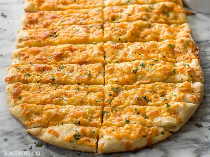 This Homemade Cheesy Garlic Bread is made from scratch with homemade dough, fresh garlic, real butter, and your favorite cheese. Budgetbytes.com Front view of sliced Cheesy Garlic Bread