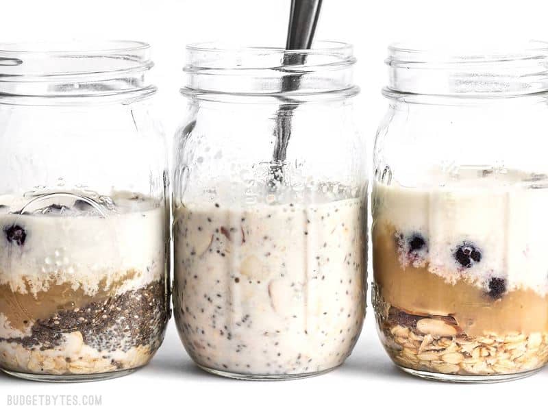 Adding milk and stirring the overnight oats in the jars.