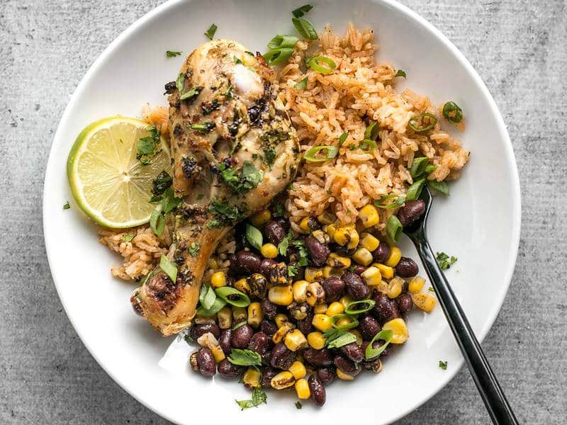 Bright and flavorful Cilantro Lime Chicken plus a classic Taco Rice and a smoky mix of corn and black beans makes an easy and hearty meal. BudgetBytes.com Cilantro Lime Chicken, taco rice, and black beans and corn on a plate
