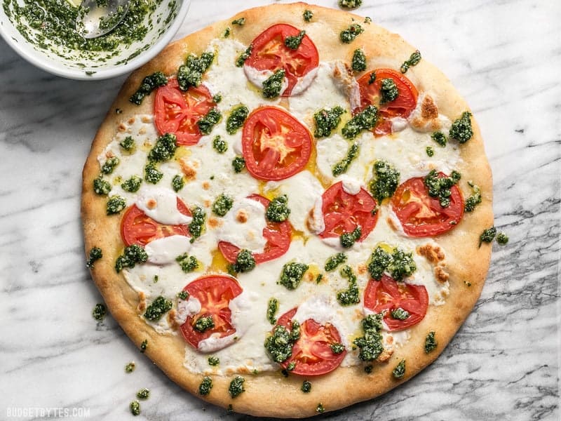 Take your Marghertia pizza up a level with a drizzle of zesty parsley pesto. This white pizza is anything but boring. BudgetBytes.com A bowl of parsley pesto next to a freshly baked white pizza
