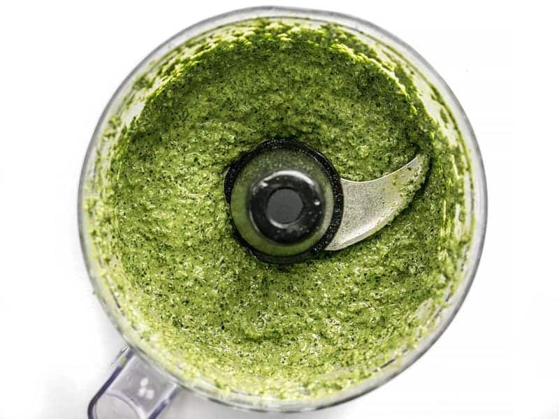Kale makes a great inexpensive and earthy pesto! Dress up this Kale Pesto pasta with add-ins to make it a meal, or keep it simple for the perfect summer side. BudgetBytes.com Pureed homemade kale pesto in the food processor bowl