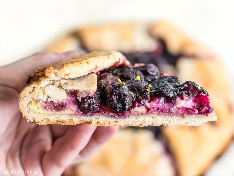This rustic Lemon Blueberry Cream Cheese Galette is a simple dessert that can be made with frozen or fresh berries. Easier than pie! Budgetbytes.com Close up side view of a slice of Lemon Blueberry Cream Cheese Galette.