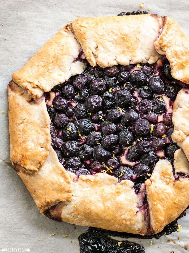 This rustic Lemon Blueberry Cream Cheese Galette is a simple dessert that can be made with frozen or fresh berries. Easier than pie! Budgetbytes.com Baked Lemon Blueberry Cream Cheese Galette with fresh lemon zest sprinkled on top