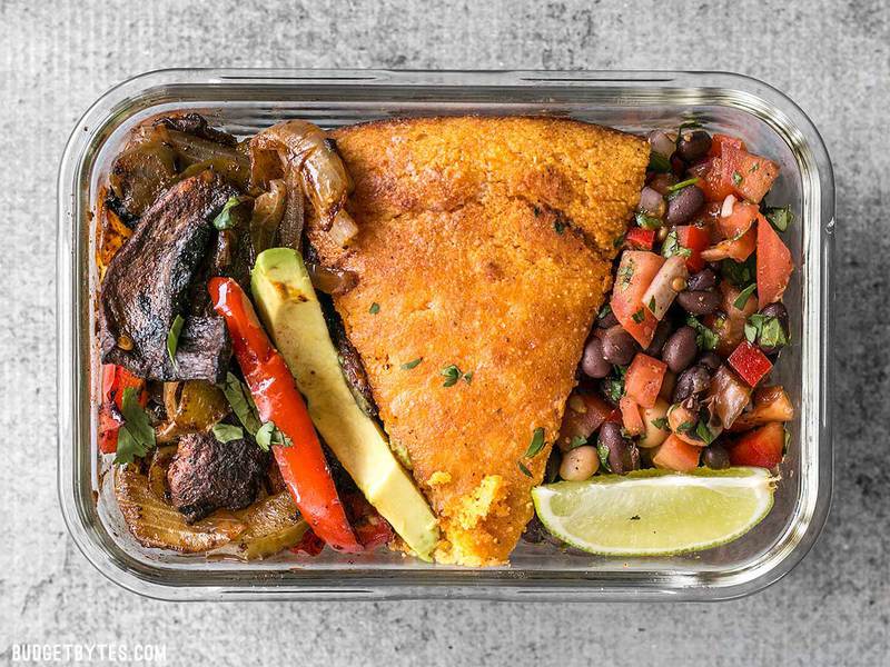 This smoky chipotle portobello fajita meal prep features mixed fajita vegetables, sweet potato cornbread, and cowboy caviar for a filling vegetarian meal! BudgetBytes.com Close up of one smoky chipotle portobello fajita meal prep container