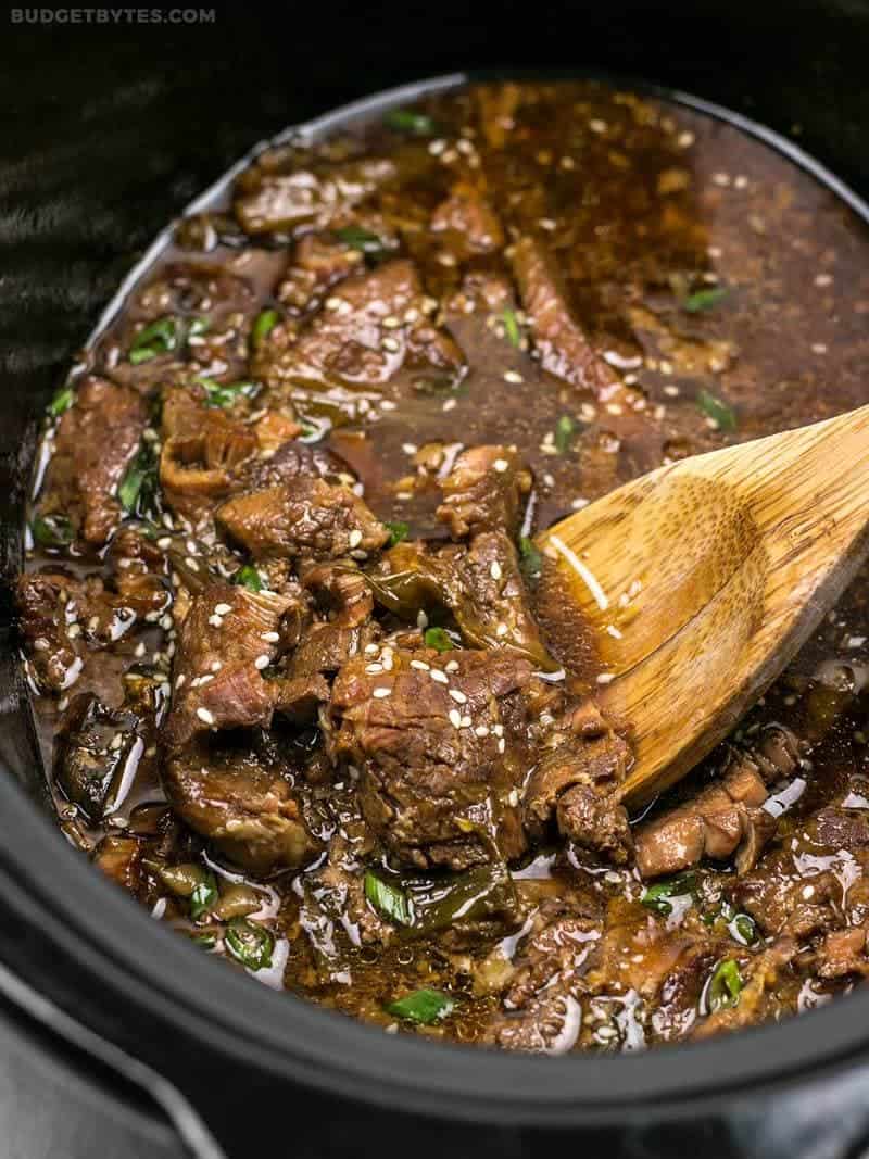 This tender, rich, and flavorful Slow Cooker Sesame Beef is extremely versatile and only requires a few ingredients that can be found at most grocery stores. BudgetBytes.com Slow Cooker Sesame Beef in the slow cooker with a wooden spoon