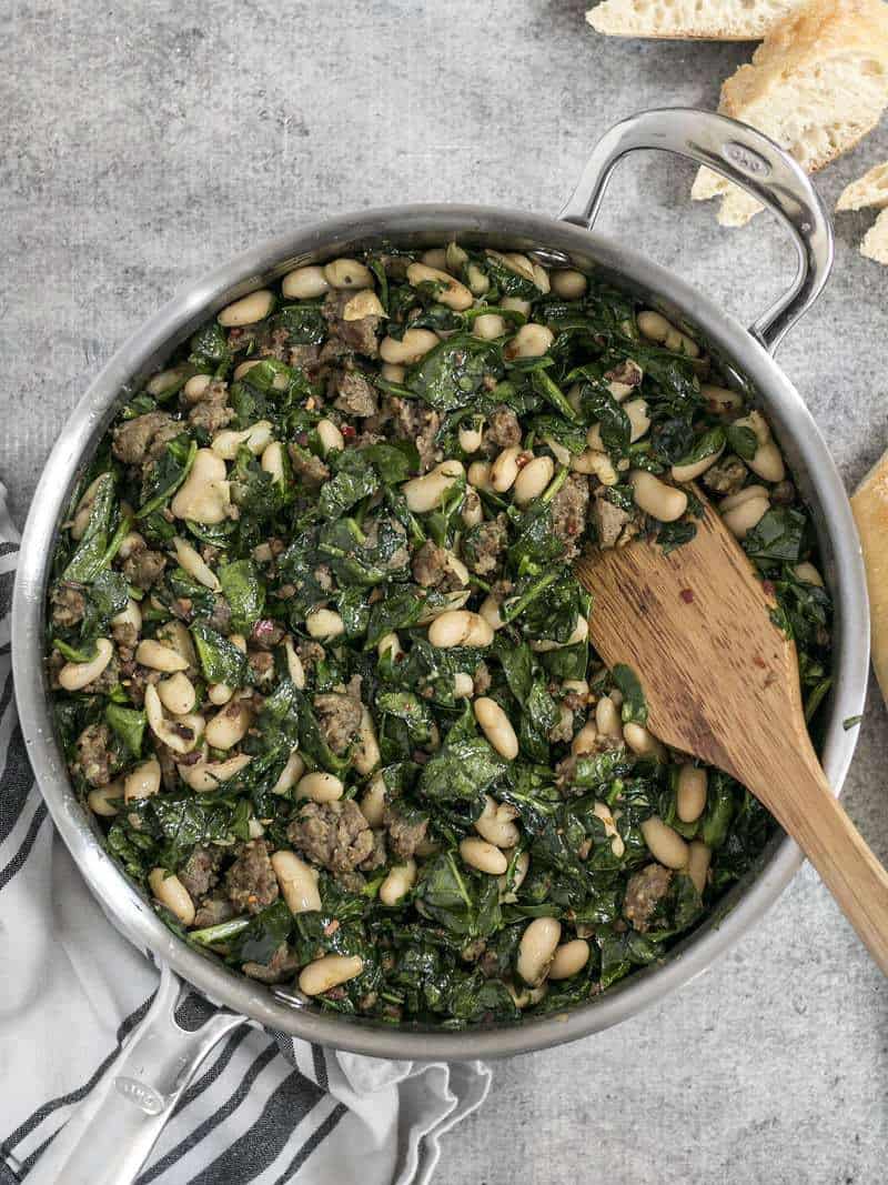 It doesn't get easier than this high protein, high fiber, high FLAVOR Italian Sausage and White Bean Skillet! BudgetBytes.com Overhead shot of the Italian Sausage and White Bean Skillet with a wooden spatula