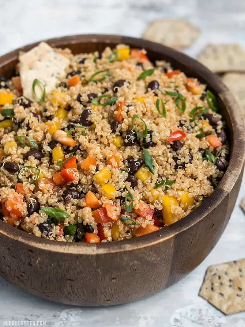 Enjoy this Smoky Quinoa and Black Bean Salad alone as a vegan meal, or as a side with grilled meat or fish. Full of flavor, color, texture and nutrients! Budgetbytes.com Smoky Quinoa and Black Bean Salad in a wooden bowl with crackers.