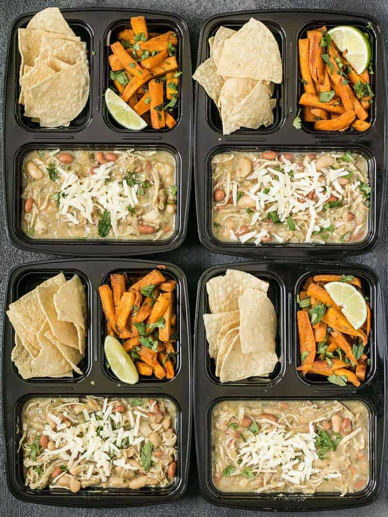 This White Chicken Chili Meal Prep includes a slow cooker chili with Cumin Lime Roasted Sweet Potatoes and tortilla chips for dipping! BudgetBytes.com Four White Chicken Chili Meal Prep containers arranged in a rectangle