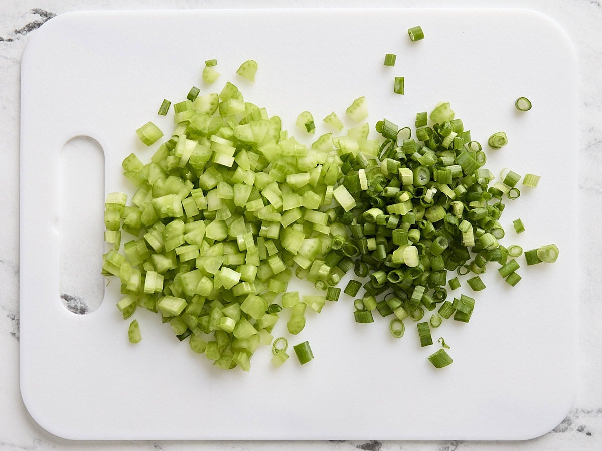 Diced celery and green onions on a cutting board.