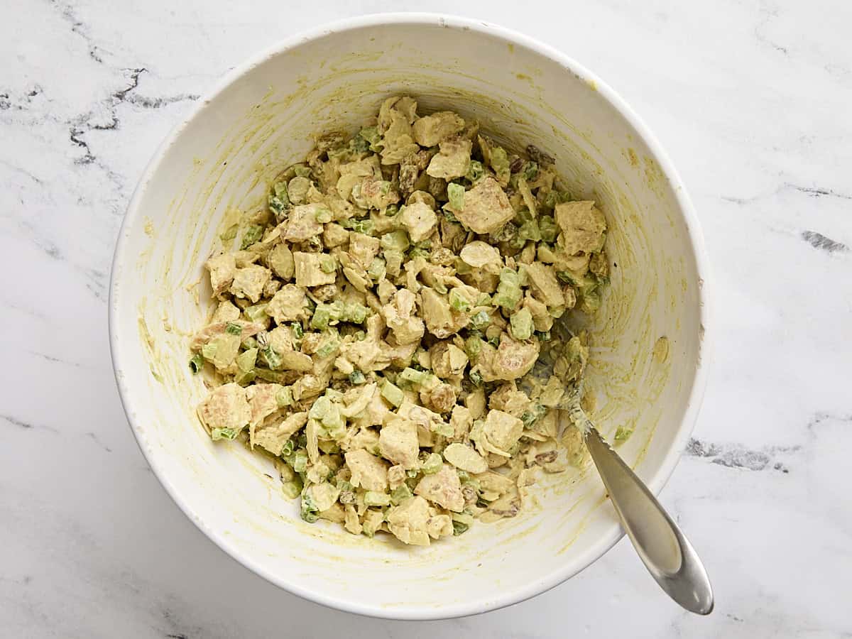 A bowl of homemade curry chicken salad with a spoon.