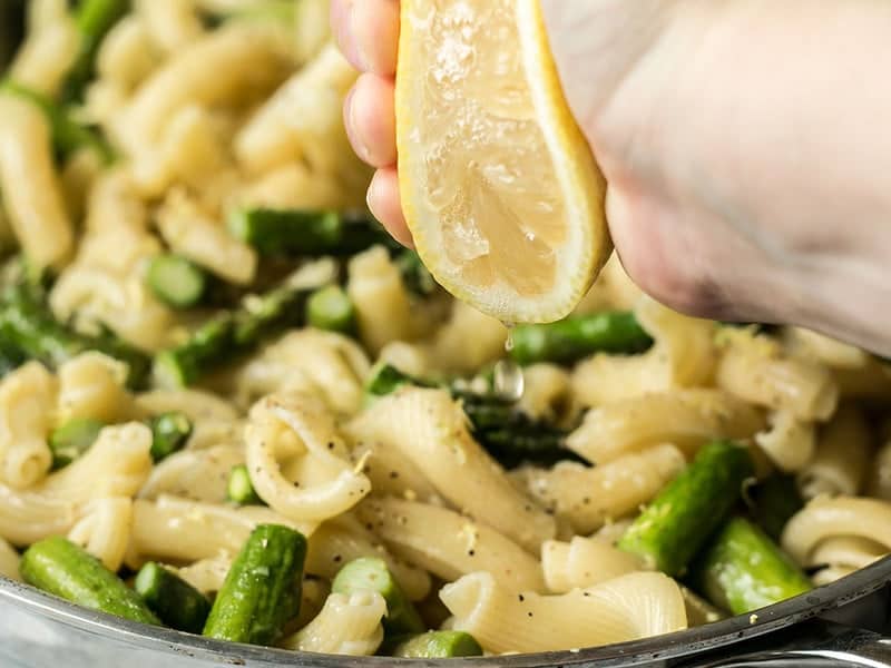 Lemon Garlic Asparagus Pasta is a fast, easy, and fresh weeknight dinner that you'll come back to again and again and have memorized in no time. BudgetBytes.com Lemon being squeezed over pasta