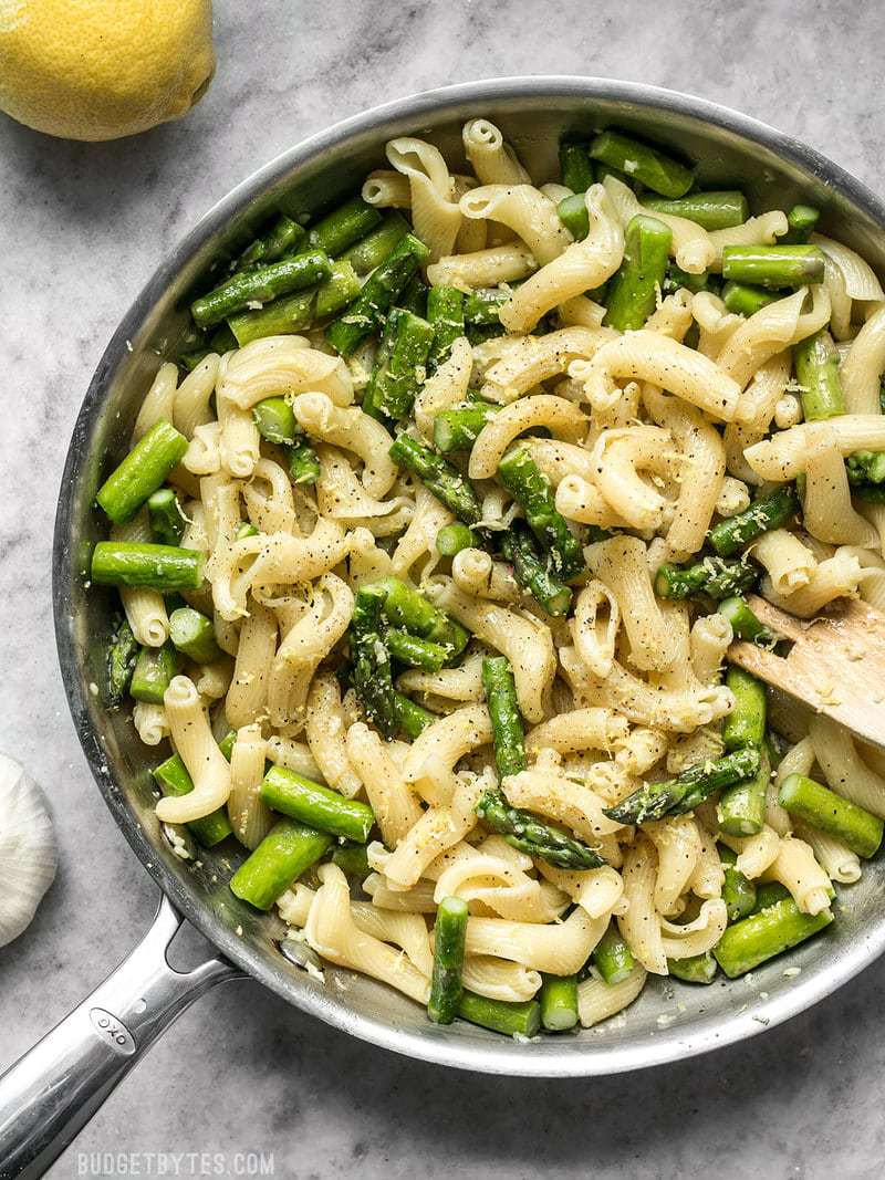 Lemon Garlic Asparagus Pasta is a fast, easy, and fresh weeknight dinner that you'll come back to again and again and have memorized in no time. BudgetBytes.com A skillet full of Lemon Garlic Asparagus Pasta with a wooden fork and lemons on the side