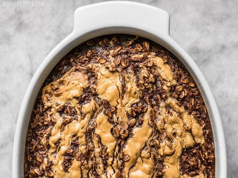 This Peanut Butter Brownie Baked Oatmeal is an indulgent-yet-healthy breakfast with rich chocolatey goodness and just a hint of sweetness. BudgetBytes.com Close up of Peanut Butter Brownie Baked Oatmeal in the casserole dish