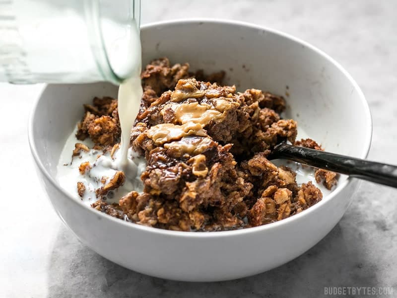 This Peanut Butter Brownie Baked Oatmeal is an indulgent-yet-healthy breakfast with rich chocolatey goodness and just a hint of sweetness. BudgetBytes.com Milk being poured onto a bowl of Peanut Butter Brownie Baked Oatmeal