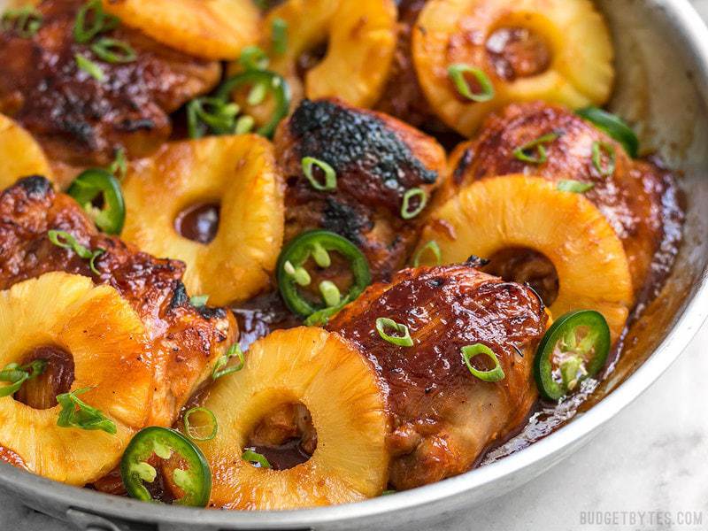 A quick pan sauce drenches tender chicken thighs and thick pineapple slices in this easy Skillet Pineapple BBQ Chicken Close up of Skillet Pineapple BBQ Chicken with thick slices of pineapple in skillet.