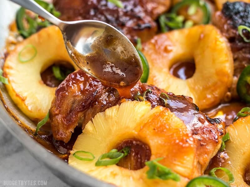 A quick pan sauce drenches tender chicken thighs and thick pineapple slices in this easy Skillet Pineapple BBQ Chicken. Budgetbytes.com Close up of BBQ sauce being drizzled over chicken thighs with slices of pineapple.