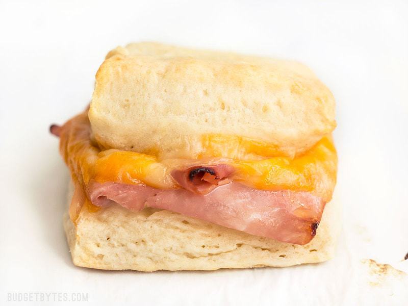 These Ham and Cheese Biscuits are a super indulgent, yet super easy treat for your weekend breakfast or to serve guests. BudgetBytes.com Close up of one Ham and Cheese Biscuit