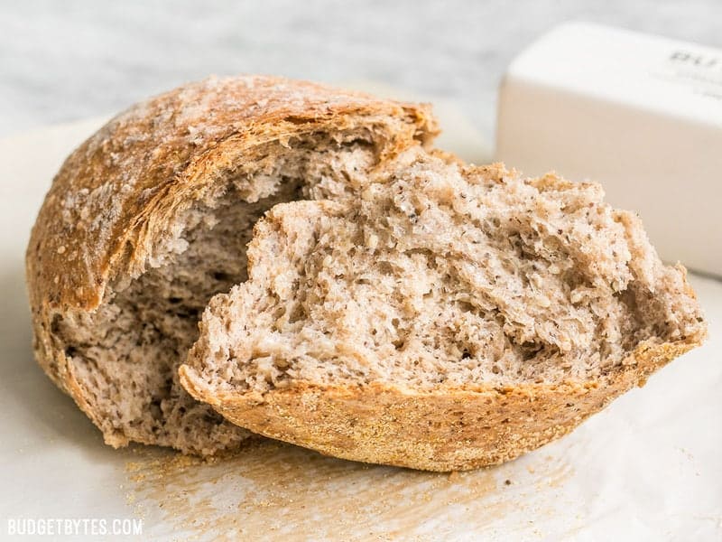 This simple homemade Seeded No-Knead Bread is packed with seeds for extra texture, flavor, and nutrients! BudgetBytes.com A loaf of Seeded No-Knead Bread torn in half.