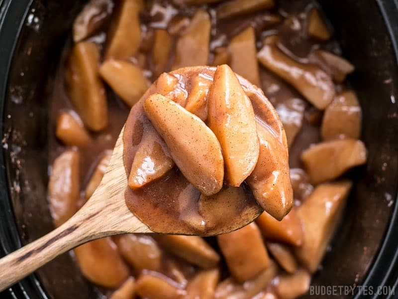 Slow Cooker Hot Buttered Apples are an easy and versatile dessert that is perfect for using up your glut of autumn apples! BudgetBytes.com Close up of a spoonful of Slow Cooker Hot Buttered Apples