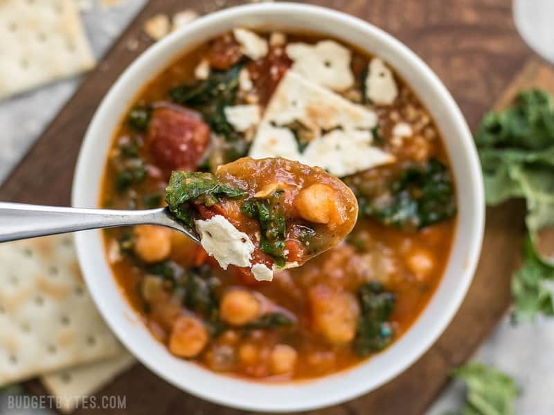This Smoky Potato Chickpea Stew is a hearty and filling plant-based dish that will keep you full and warm this winter! BudgetBytes.com Close up of a spoonful of Smoky Potato Chickpea Stew with the bowl in the background.