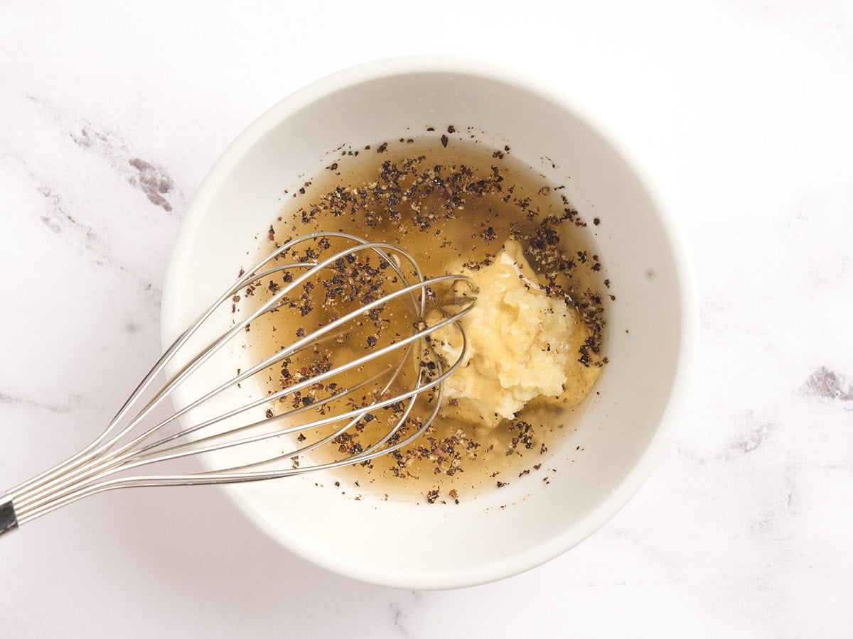 Kale salad dressing being whisked in a bowl.