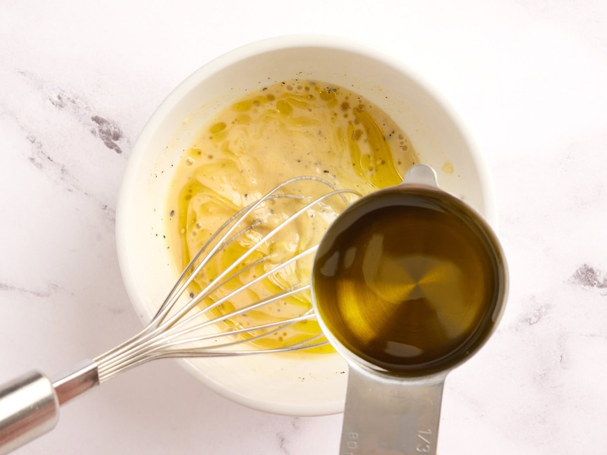 Oil being whisked into a kale salad dressing.