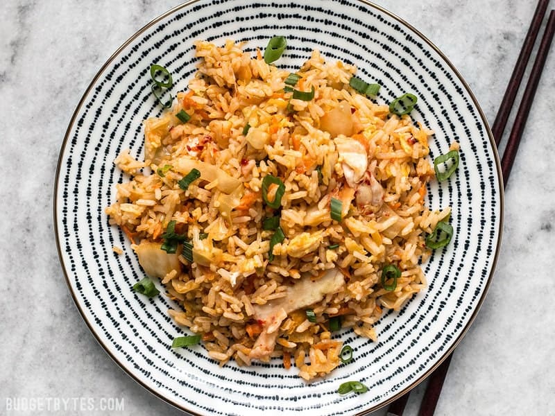 This Kimchi Fried rice is tangy, spicy, and the perfect way to use up all the leftover ingredients and scraps in your kitchen. BudgetBytes.com A plate of Kimchi Fried rice with chopsticks on the side