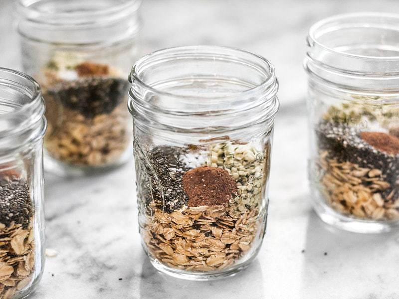 Preparing individual oat packs with seeds, seasoning, and other add-ins, like these Make Ahead Seeded Oats, makes having a healthy breakfast fast and easy. BudgetBytes.com Multiple jars full of Make Ahead Seeded Oats