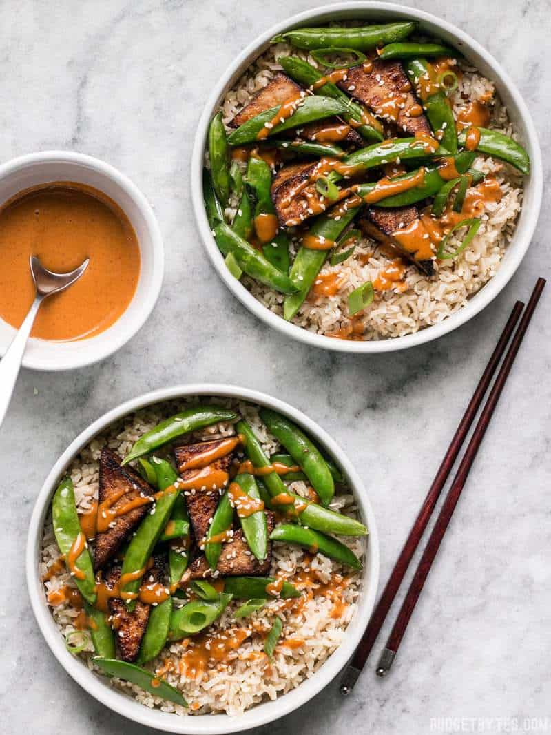 These vegan Soy Marinated Tofu Bowls are full of rich flavors and plenty of texture to keep your taste buds happy and your belly full. BudgetBytes.com Two Soy Marinated Tofu Bowls with Spicy Peanut Sauce on the Side