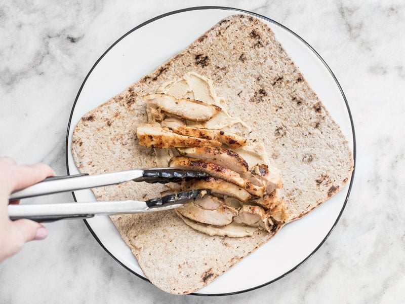 Adding chicken to the hummus covered flatbread.