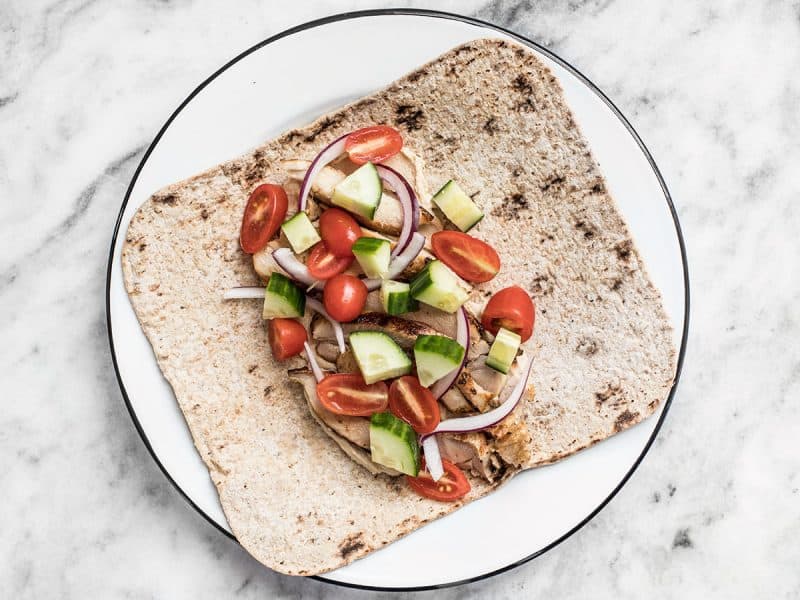 Adding vegetables to the flatbread.