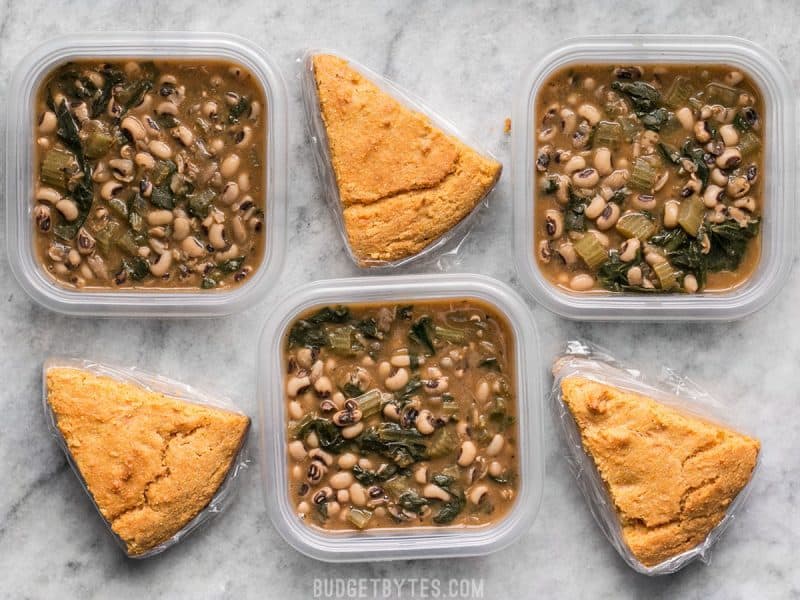 This Black Eyed Peas Meal Prep is comfort food defined and will keep you full, warm, and cozy during these cold winter days. BudgetBytes.com Three Black Eyed Peas Meal Prep containers alternating with cornbread slices