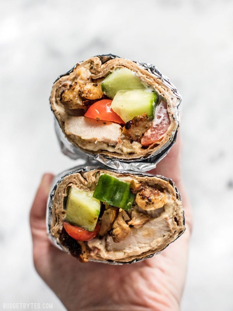 Prep the ingredients for these Greek Chicken Wraps to keep on hand to build fresh wraps or salads all week. BudgetBytes.com Close up of Greek Chicken Wraps in aluminum foil.