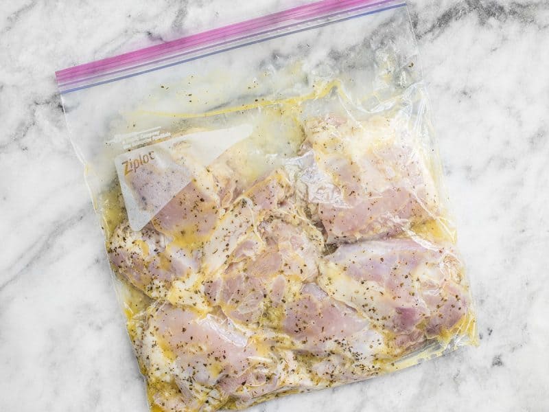 Chicken marinating in a Ziploc bag.
