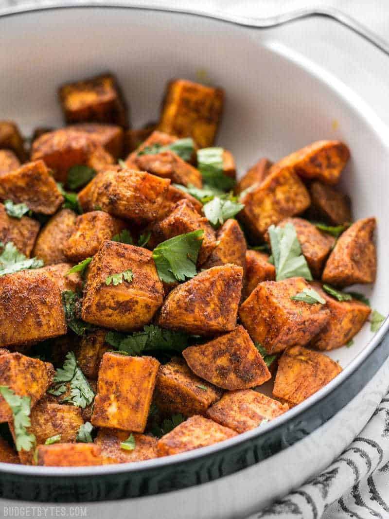 Spicy, aromatic, and earthy, these Moroccan Spiced Sweet Potatoes will add an adventurous flavor to any dinner! BudgetBytes.com Close up of Moroccan Spiced Sweet Potatoes in dish with cilantro