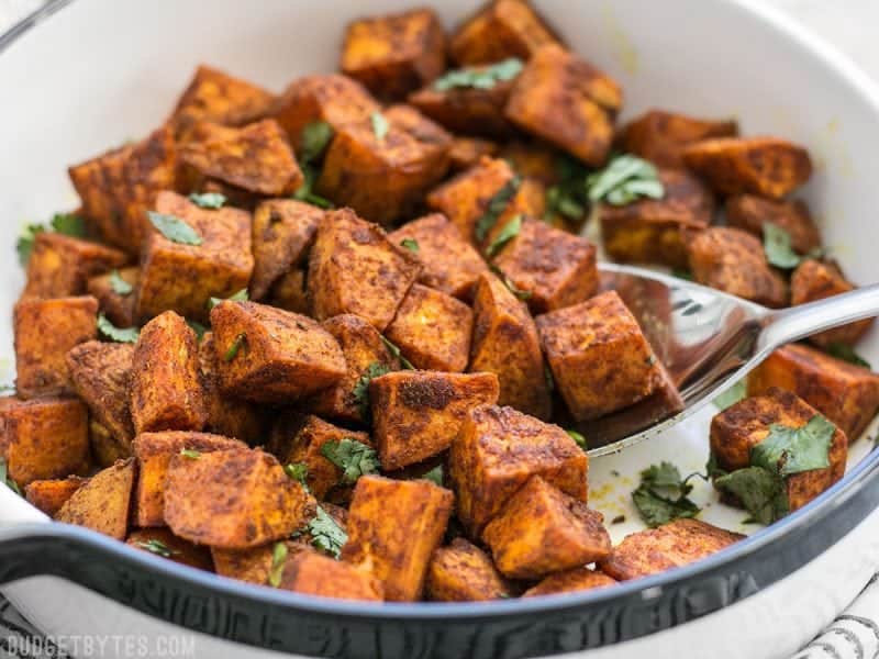 Spicy, aromatic, and earthy, these Moroccan Spiced Sweet Potatoes will add an adventurous flavor to any dinner! BudgetBytes.com Close up of Moroccan Spiced Sweet Potatoes being scooped out of a dish