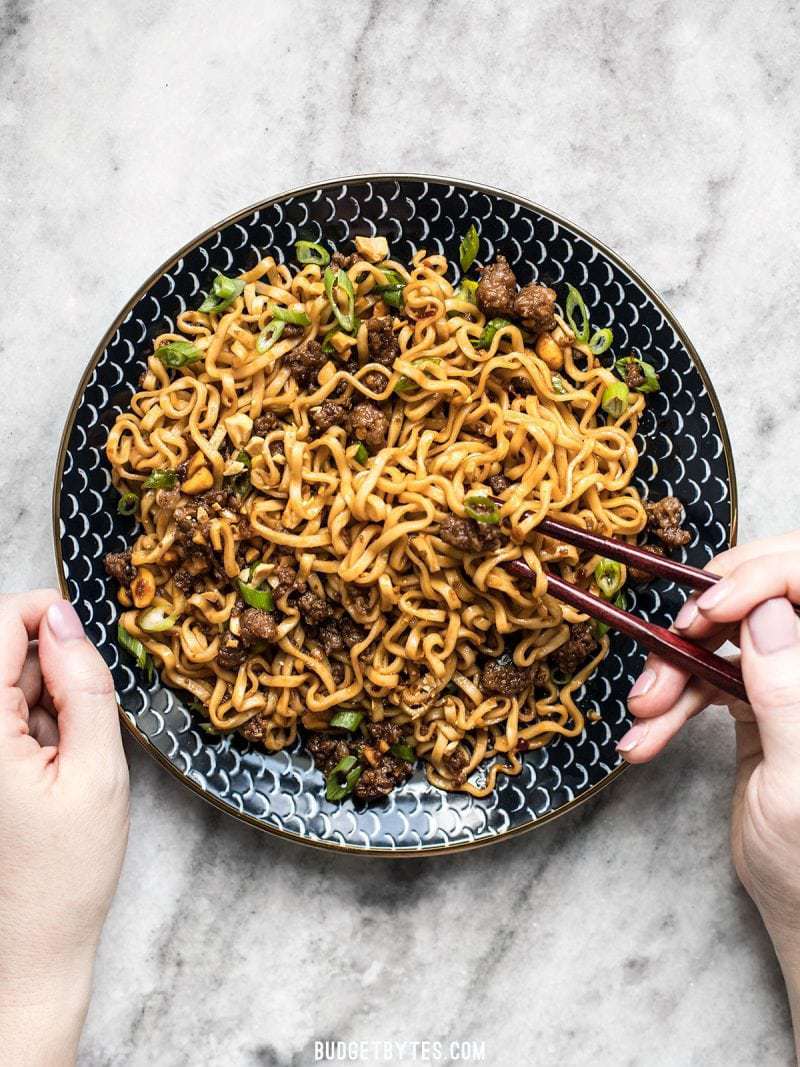 Sweet, salty, rich, and crunchy, these Pork and Peanut Dragon Noodles hit all the bases. It’s fast, easy comfort food for busy nights! BudgetBytes.com A big plate of Pork and Peanut Dragon Noodles being eaten with chopsticks