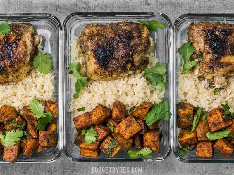 This Pressure Cooker Chicken and Rice Meal Prep combines spicy Moroccan Spiced Sweet Potatoes with tender chicken and savory rice. BudgetBytes.com Three Pressure Cooker Chicken and Rice Meal Prep containers in a row