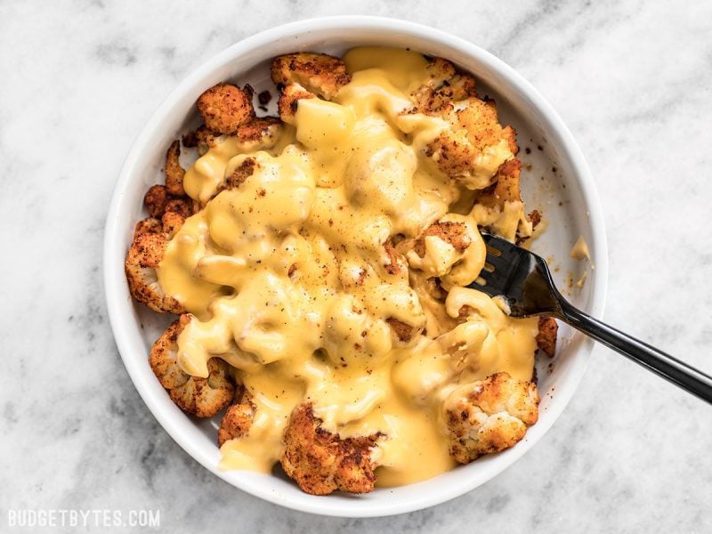 Spicy Roasted Cauliflower with Cheese Sauce is a delicious low-carb way to get your rich, creamy, cheesy fix! Step by step photos. Budgetbytes.com Finished Spicy Roasted Cauliflower with Cheese Sauce ready to eat in a bowl