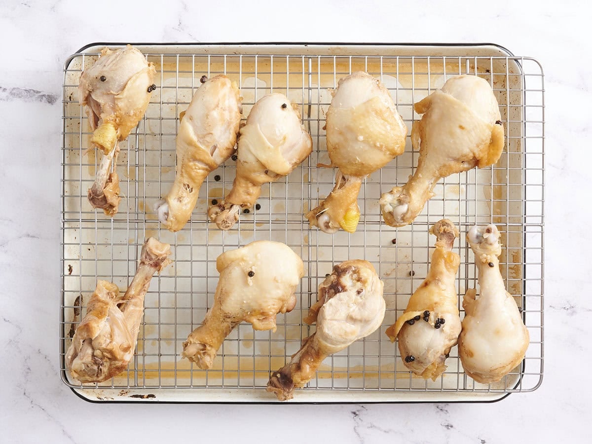 Browned chicken drumsticks on a wire rack set over a baking tray
