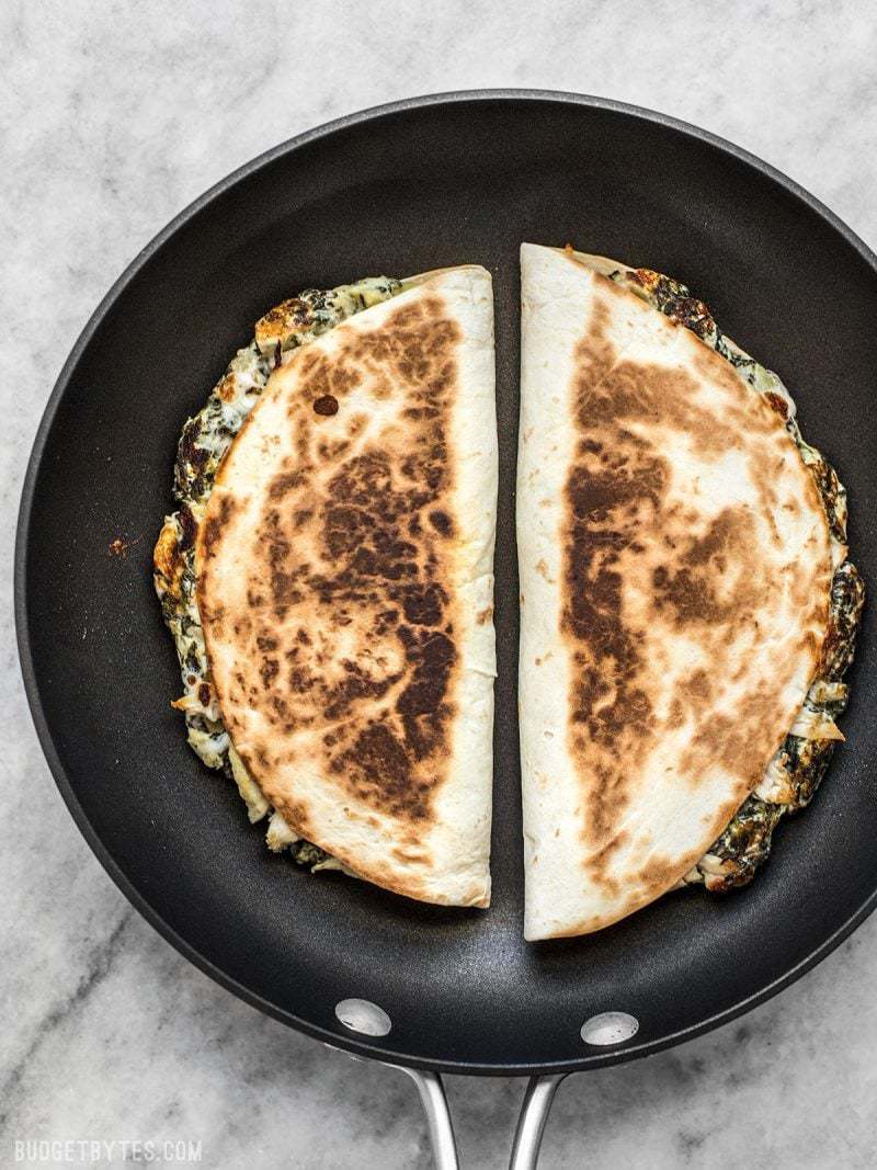 Use your leftover party dips to make a delicious lunch the next day, like these super creamy Spinach Artichoke Quesadillas. Budgetbytes.com Two Spinach Artichoke Quesadillas being toasted in a skillet
