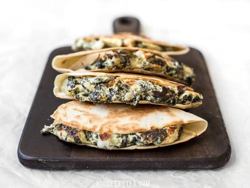 Use your leftover party dips to make a delicious lunch the next day, like these super creamy Spinach Artichoke Quesadillas. Budgetbytes.com Front view of overstuffed Spinach Artichoke Quesadillas stacked on a cutting board